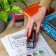 Kind zeigt stolz ein Arbeitsblatt mit Lehrer-Stempel im Klassenzimmer